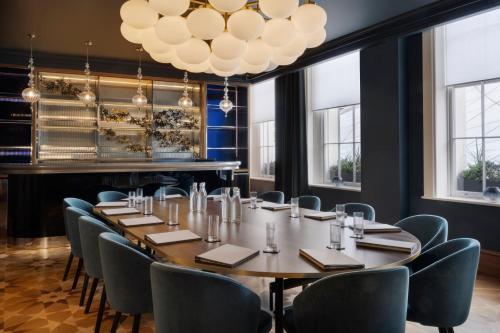 a large table in a room with chairs and a chandelier at Kaya Great Northern Hotel, London in London