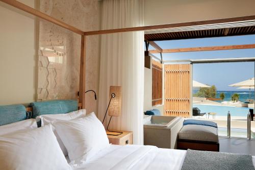 a bedroom with a bed and a view of the ocean at Domes Noruz Chania, Autograph Collection- Adults Only in Kato Daratso