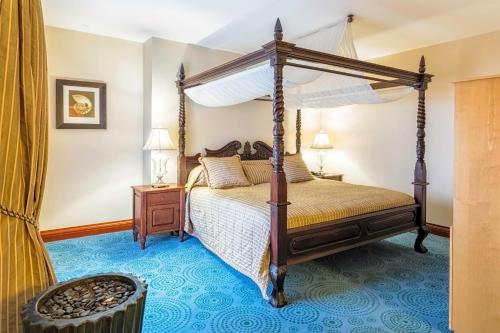 a bedroom with a canopy bed and a blue carpet at Protea Hotel by Marriott Walvis Bay Pelican Bay in Walvis Bay