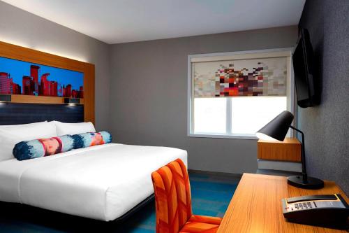 a bedroom with a bed and a table and a window at Aloft Hotel Calgary University in Calgary