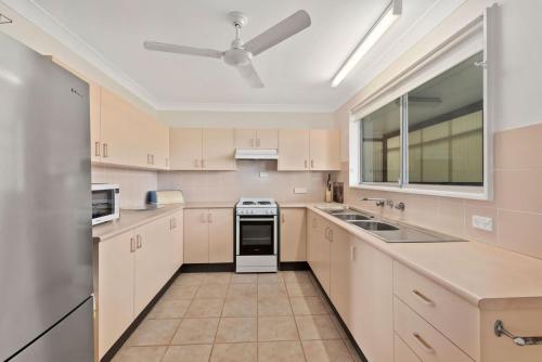 a kitchen with white cabinets and a ceiling fan at Lens Retreat in Arrawarra