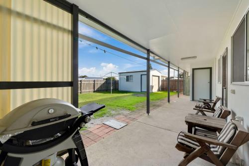 a patio with a grill and chairs and a building at Lens Retreat in Arrawarra