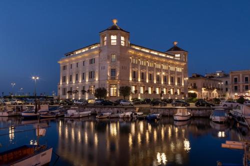 敘拉古的住宿－Ortea Palace Hotel, Sicily, Autograph Collection，码头上的一个大型建筑,晚上有船只