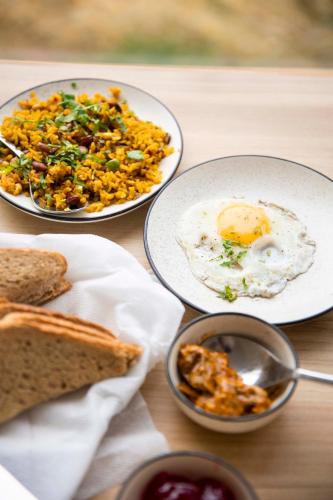 a table with three plates of food with eggs and bread at The Kamru Riverside Camps and Resorts in Sāngla