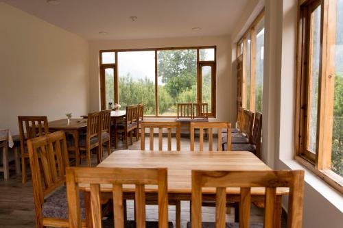 a dining room with wooden tables and chairs and windows at The Kamru Riverside Camps and Resorts in Sāngla