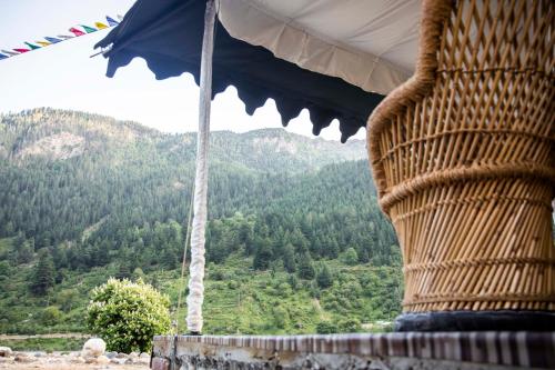 a person standing under an umbrella looking at a mountain at The Kamru Riverside Camps and Resorts in Sāngla