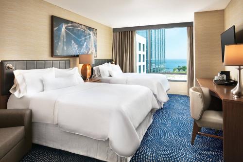 two beds in a hotel room with a large window at The Westin Milwaukee in Milwaukee
