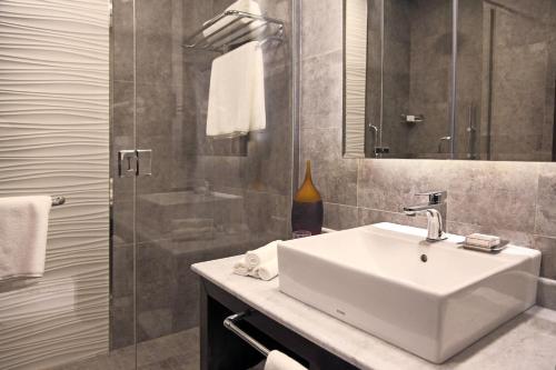 ein Bad mit einem Waschbecken, einem Spiegel und einer Dusche in der Unterkunft Marriott Executive Apartments Madinah in Medina