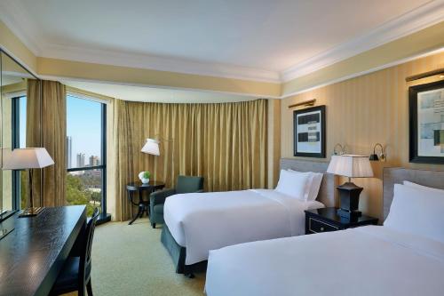 a hotel room with two beds and a desk at The Ritz-Carlton, Bahrain in Manama