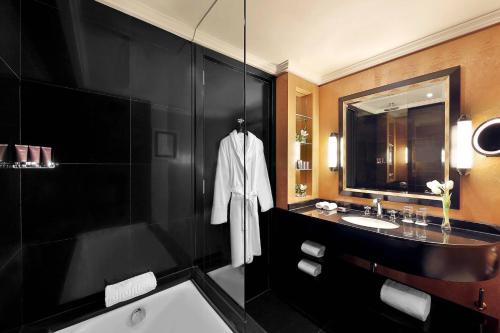 ein Badezimmer mit einer Badewanne, einem Waschbecken und einem Spiegel in der Unterkunft The Ritz-Carlton, Bahrain in Manama