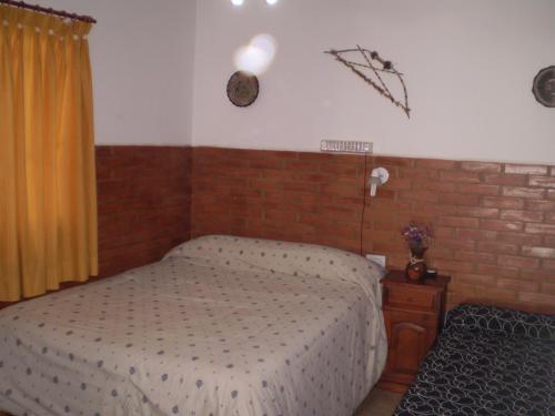 1 dormitorio con cama y pared de ladrillo en Hotel Foxes en Villa del Dique