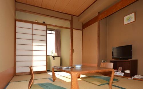 a living room with a table and a tv at Onoya Hotel in Tagajo