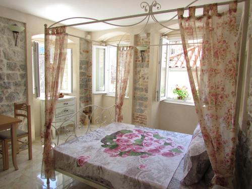 a bedroom with a canopy bed with flowers on it at Apartments Popovic in Kotor