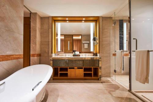 a bathroom with a tub and a sink and a mirror at Sheraton Chuzhou Hotel in Chuzhou