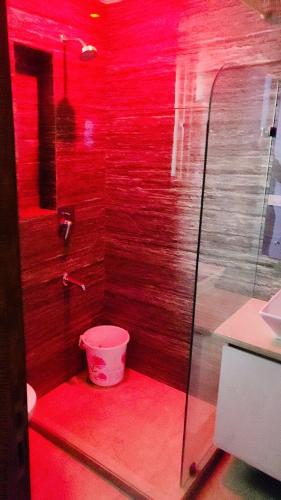 a bathroom with red lighting and a bucket at Vinanda Home Stay in New Delhi