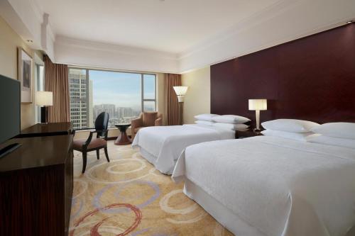 a hotel room with two beds and a desk at Sheraton Ningbo Hotel - Tianyi Square in Ningbo
