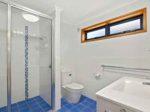a bathroom with a shower and a toilet and a sink at Surf Break in Arrawarra
