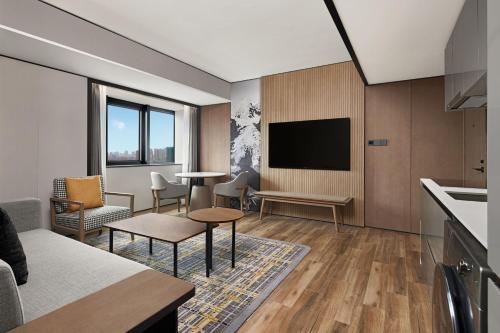 a living room with a flat screen tv and a kitchen at Sheraton Chengdu Lido Hotel in Chengdu