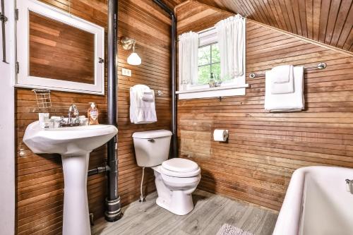 a bathroom with a toilet and a sink and a tub at Lakeside Cottage on Katherine in Hazelhurst