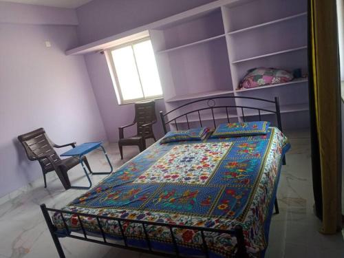 a bedroom with a bed and two chairs and a window at Sathya Sai Nivas in Puttaparthi