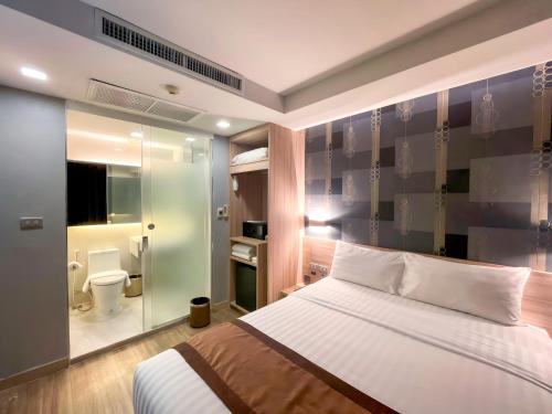 a bedroom with a bed and a bathroom with a toilet at Aspira Sukhumvit in Bangkok