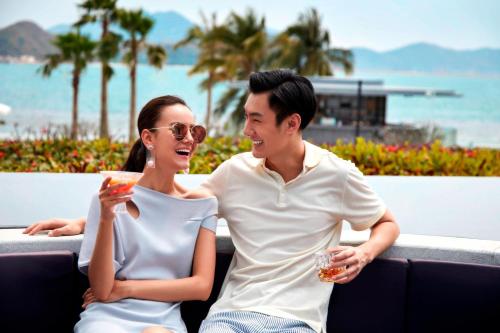 a man and a woman sitting on a bench with drinks at The Shanhaitian Resort Sanya, Autograph Collection in Sanya