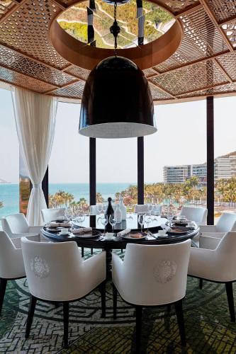 a dining room with a table and chairs and the ocean at The Shanhaitian Resort Sanya, Autograph Collection in Sanya