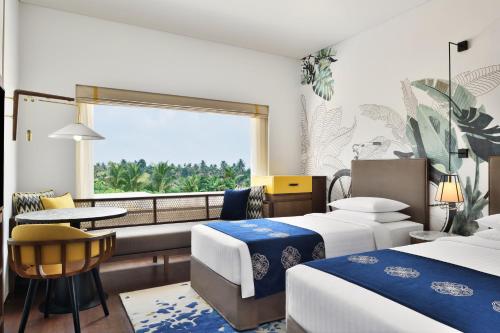 een hotelkamer met 2 bedden en een raam bij Port Muziris, A Tribute Portfolio Hotel in Nedumbassery
