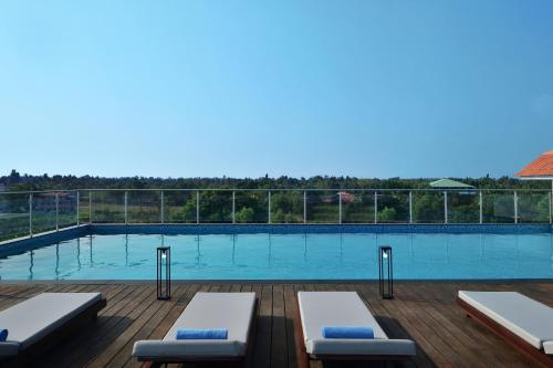 - une piscine avec deux chaises longues sur une terrasse en bois dans l'établissement Port Muziris, A Tribute Portfolio Hotel, à Nedumbassery