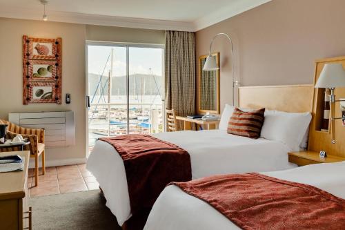 a hotel room with two beds and a balcony at Protea Hotel by Marriott Knysna Quays in Knysna