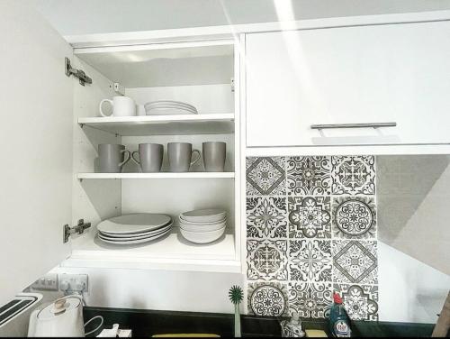 a kitchen with plates and dishes on shelves at The Chic Nexus Apartment 2023 New-Build in Oxford