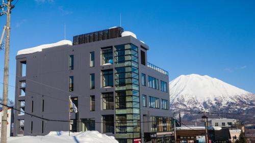 a building with a snow covered mountain in the background at hirafu188 in Kutchan