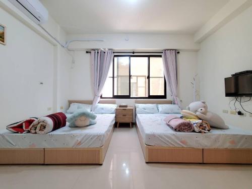 two beds sitting in a room with a window at 河畔暮光-台南安平包棟民宿villa in Anping