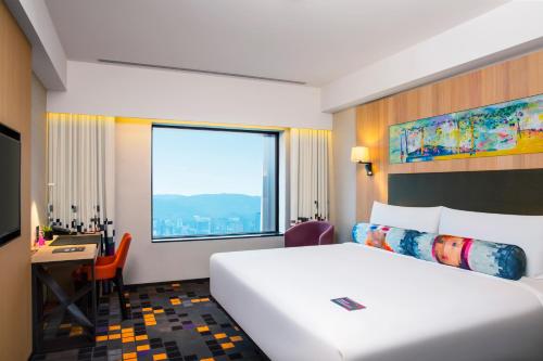 a hotel room with a bed and a desk and a window at Aloft Taipei Beitou in Taipei