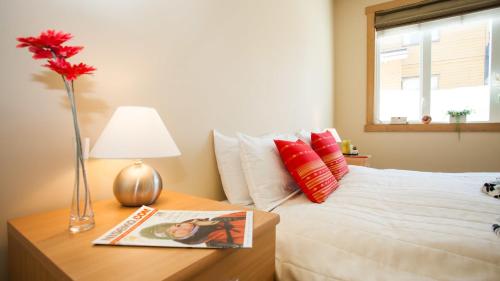 a bedroom with a bed with a vase of flowers on a table at Kamakura Apartments in Kutchan