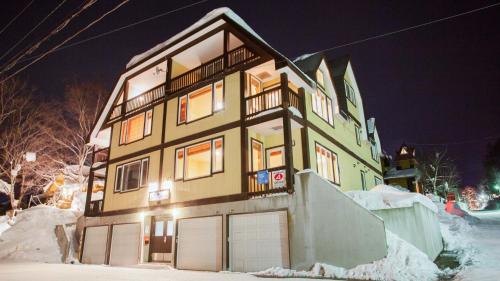 a house with two garage doors in the snow at Kamakura Apartments in Kutchan