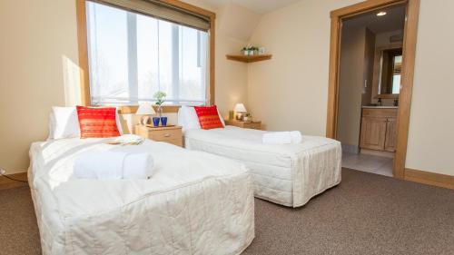 two white beds in a room with a window at Kamakura Apartments in Niseko