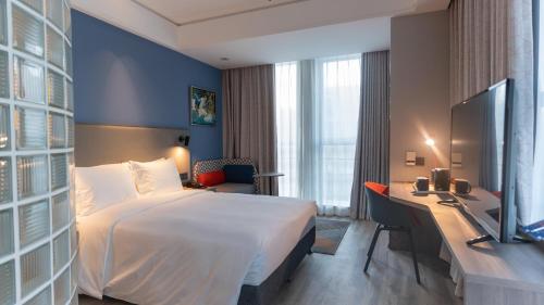 Habitación de hotel con cama grande y escritorio. en Holiday Inn Express Nantong Xinghu, an IHG Hotel, en Nantong