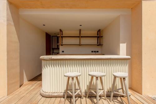 a kitchen with three stools at a counter in a room at Lumina at The Village Luxury Residences in Corasol in Playa del Carmen