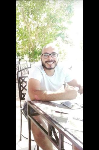 a man with glasses sitting at a table at ادهم هيبه in Alexandria