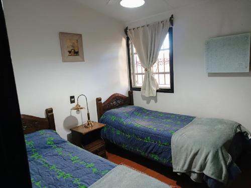 1 dormitorio con 2 camas y ventana en Complejo Los Aromos, San Juan, AR en San Juan
