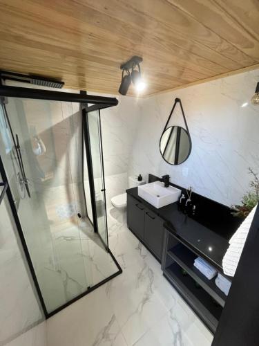 a bathroom with a sink and a glass shower at Chalé Alqualondë -Chácara Valfenda in São Joaquim