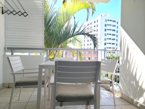 a balcony with chairs and a table and a palm tree at Mooloolaba Beach Club Paradise 2 Bedroom Apartment in Mooloolaba