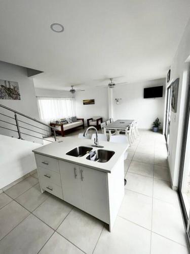 a kitchen with a sink and a living room at Pacific Breeze House - with private pool in Jacó