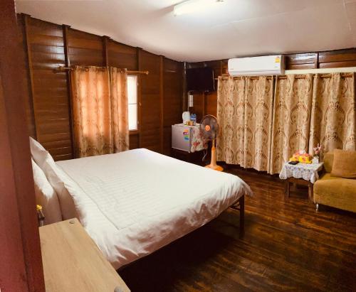 a bedroom with a bed and a chair in a room at Banthai Guesthouse in Phetchaburi