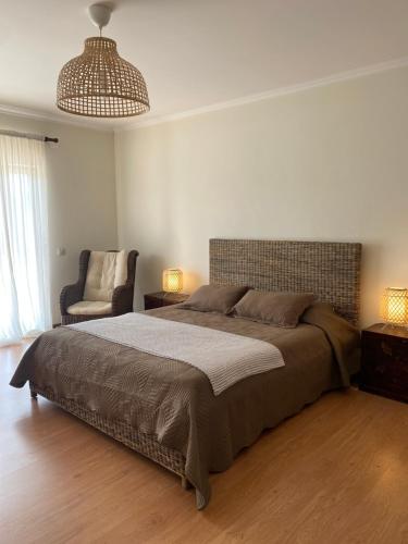 a bedroom with a large bed and a chair at A casa das minhas netas in Caldas da Rainha