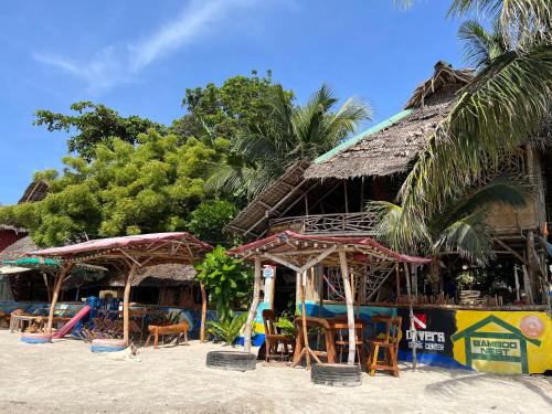 a beach with a resort with chairs and a playground at Bamboo Nest Beachfront Floating Tent in Puerto Princesa City