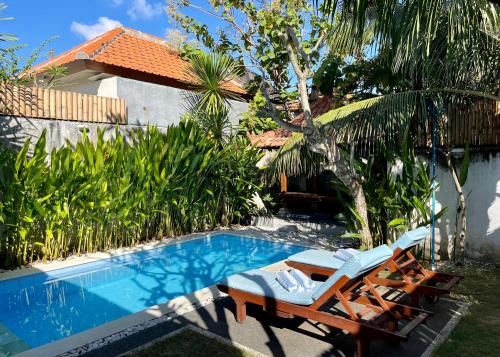 a pool with two lounge chairs next to a house at Villa Majegau 2 by Deasha in Seminyak