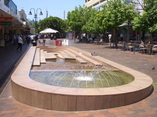 a fountain in the middle of a street with people walking around at Private Bath Ensuite Room Eastwood/MQ Uni park in Sydney