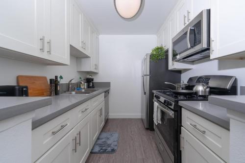 a kitchen with white cabinets and a black refrigerator at Universal Studios 8 min drive Two bedroom Apartment with free parking in Los Angeles